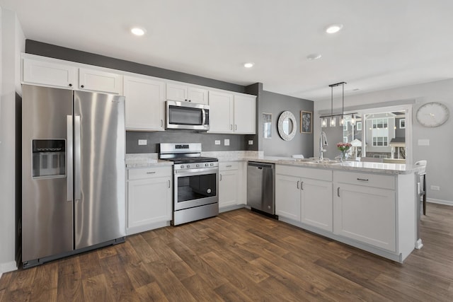 kitchen with dark wood-type flooring, a peninsula, white cabinets, stainless steel appliances, and a sink