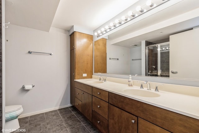 full bathroom with double vanity, a sink, toilet, and baseboards