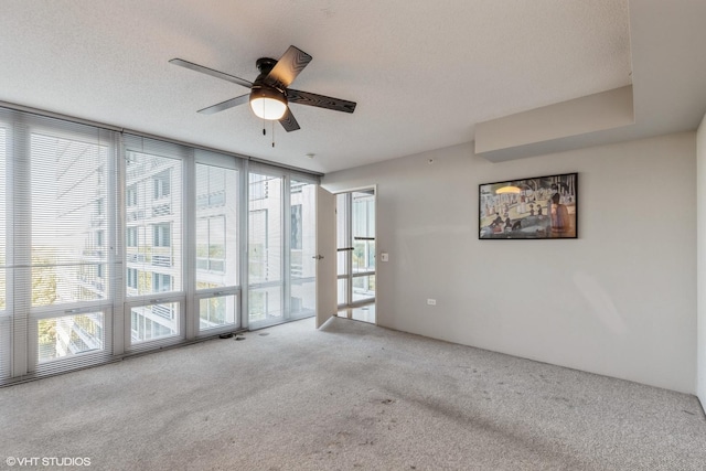 spare room featuring floor to ceiling windows, light colored carpet, ceiling fan, and a textured ceiling