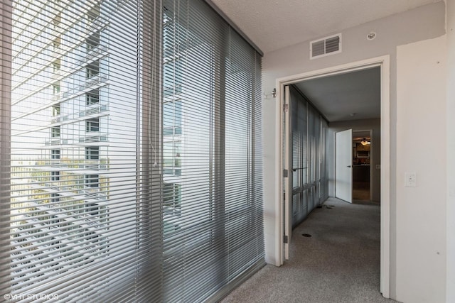 hall featuring visible vents, a textured ceiling, and carpet flooring