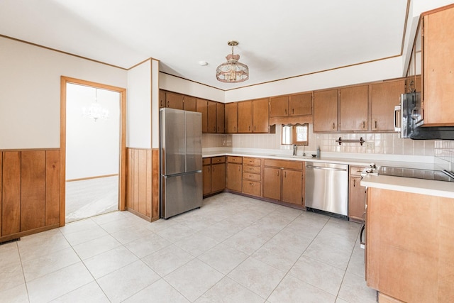 kitchen with wainscoting, light countertops, stainless steel appliances, a chandelier, and a sink