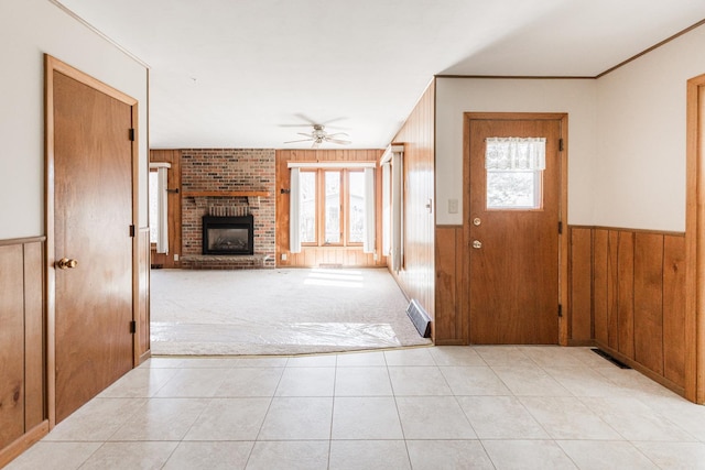 entrance foyer featuring wood walls, a fireplace, a wealth of natural light, and wainscoting