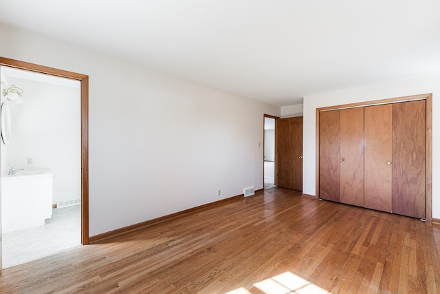 unfurnished bedroom with light wood-type flooring, baseboards, visible vents, and a closet