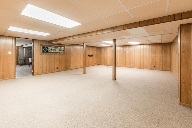 finished below grade area with a drop ceiling, wood walls, and carpet