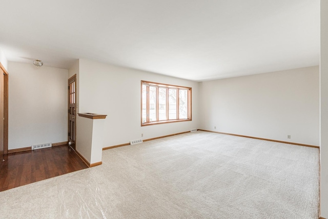 spare room with carpet floors, baseboards, and visible vents