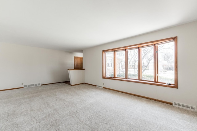 unfurnished room with visible vents, light carpet, and baseboards