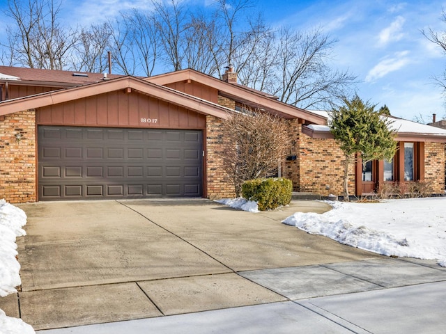 view of front of house with a garage, a chimney, concrete driveway, and brick siding