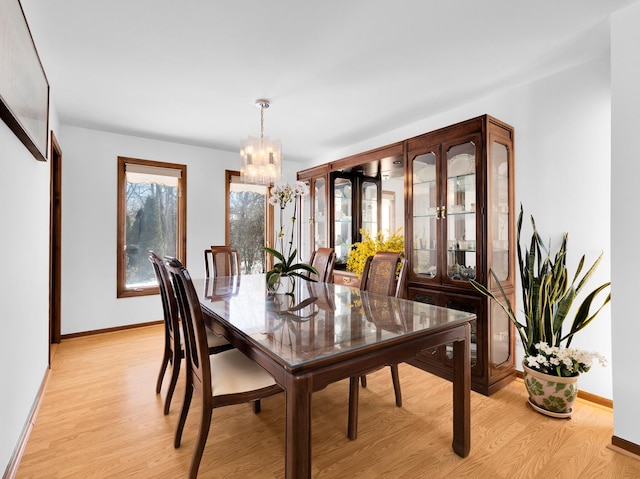 dining area featuring light wood-style flooring, baseboards, and an inviting chandelier