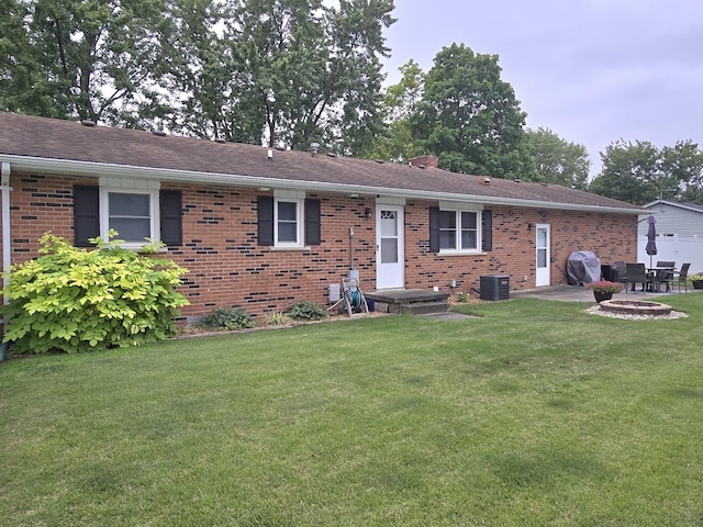 single story home featuring brick siding, a patio, a chimney, a front yard, and central AC