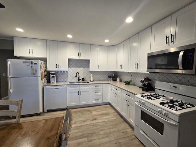 kitchen with white appliances, a sink, light wood-style floors, white cabinets, and light countertops