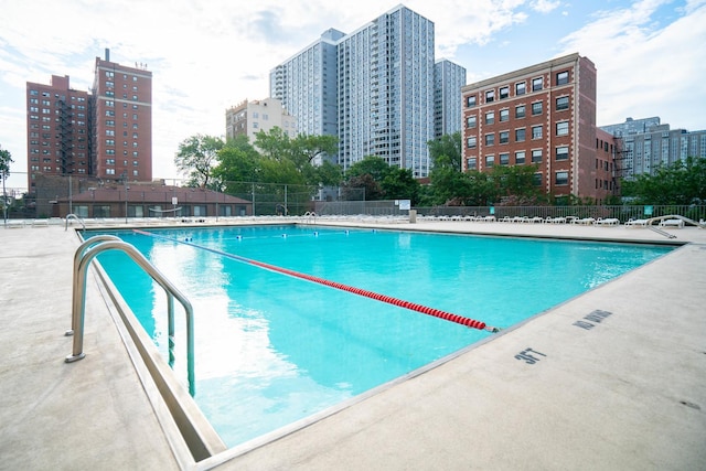 community pool with fence and a city view