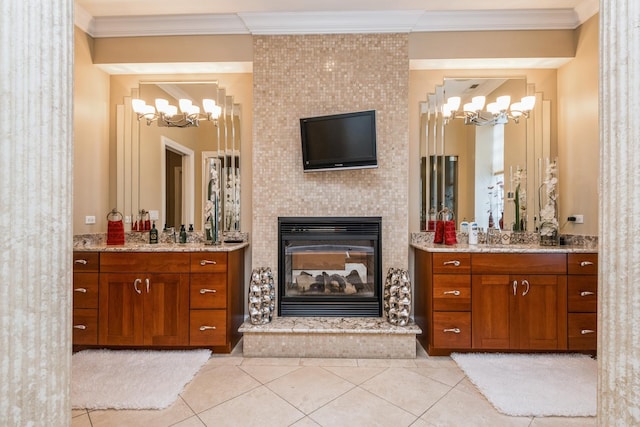 full bathroom with tile patterned flooring, a glass covered fireplace, two vanities, and ornamental molding