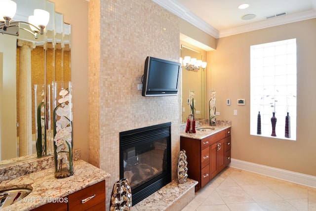 bathroom featuring visible vents, ornamental molding, an inviting chandelier, vanity, and a tile fireplace