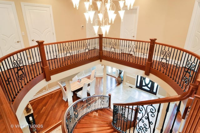 stairs featuring wood finished floors, a high ceiling, and a chandelier