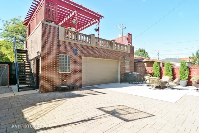 back of house featuring brick siding, stairway, concrete driveway, a garage, and a pergola