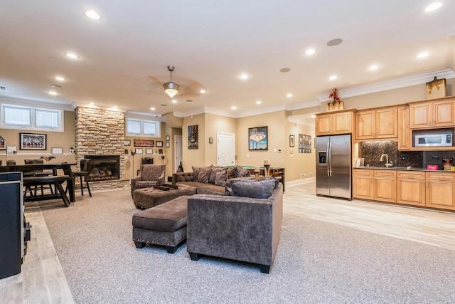 living room featuring recessed lighting, light wood-type flooring, a fireplace, and crown molding