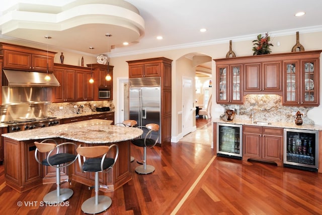 kitchen featuring wine cooler, arched walkways, under cabinet range hood, and stainless steel appliances