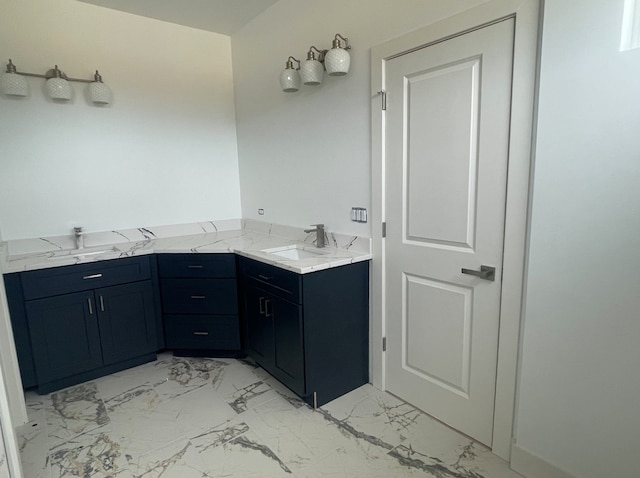 full bath featuring marble finish floor, double vanity, and a sink