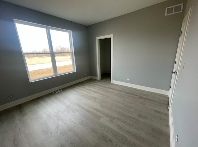 spare room with light wood-style flooring, visible vents, and baseboards