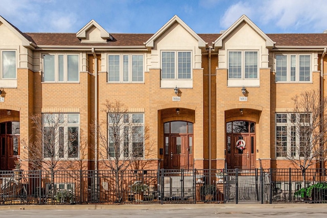 multi unit property featuring brick siding and a fenced front yard