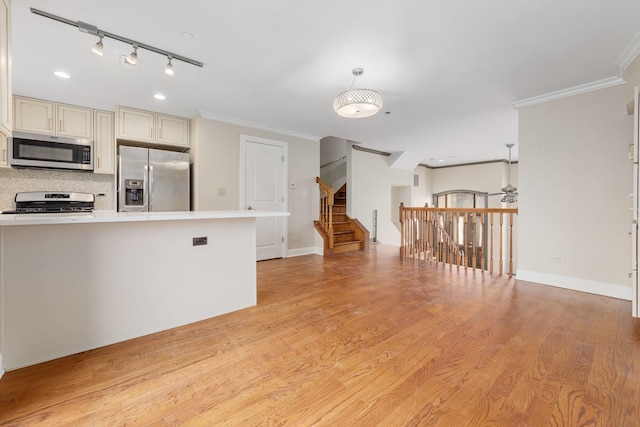 kitchen featuring light wood-style flooring, light countertops, appliances with stainless steel finishes, tasteful backsplash, and crown molding