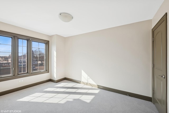 spare room featuring light colored carpet and baseboards