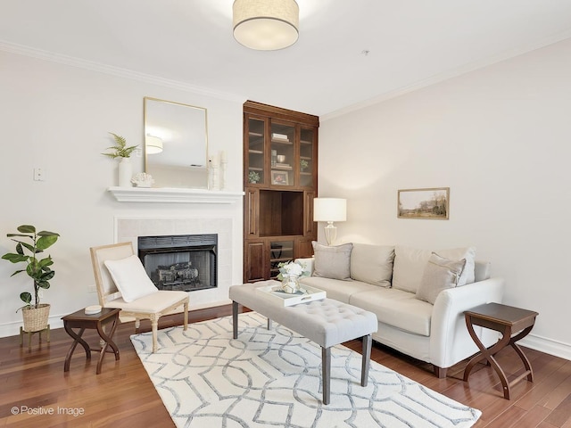 living room with ornamental molding, a fireplace, wood finished floors, and baseboards