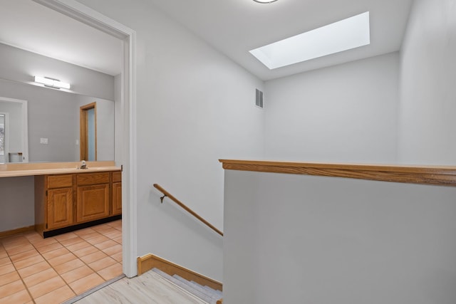 stairs featuring a skylight, tile patterned flooring, visible vents, and baseboards