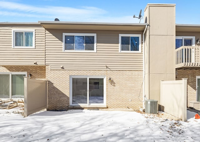 snow covered house featuring cooling unit and brick siding