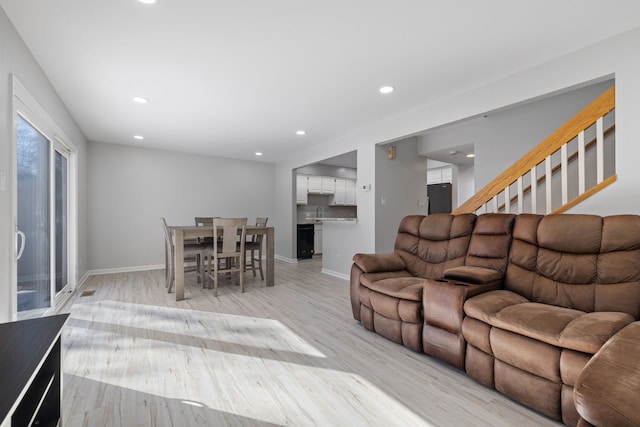 living area with stairway, light wood-style flooring, baseboards, and recessed lighting