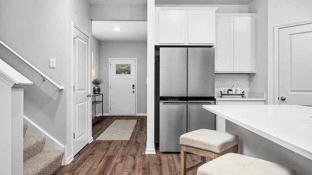 kitchen with light countertops, dark wood-style flooring, freestanding refrigerator, and white cabinets