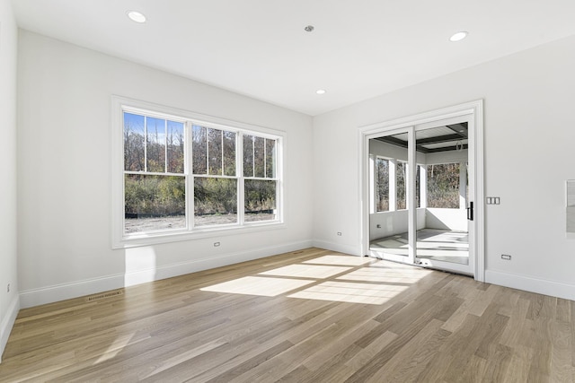 spare room with a wealth of natural light, light wood-style flooring, and baseboards