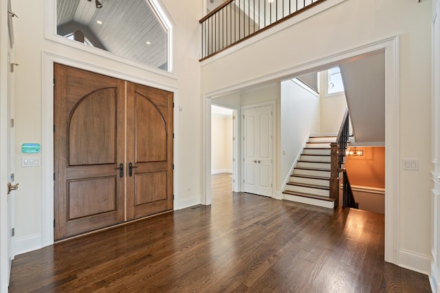 foyer featuring a high ceiling, stairway, dark wood finished floors, and baseboards