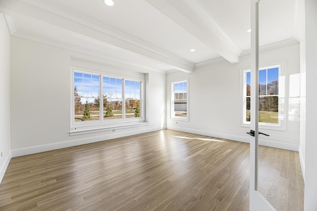 interior space with baseboards, ornamental molding, beam ceiling, and wood finished floors