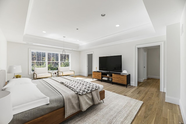 bedroom featuring light wood-type flooring, a raised ceiling, baseboards, and recessed lighting