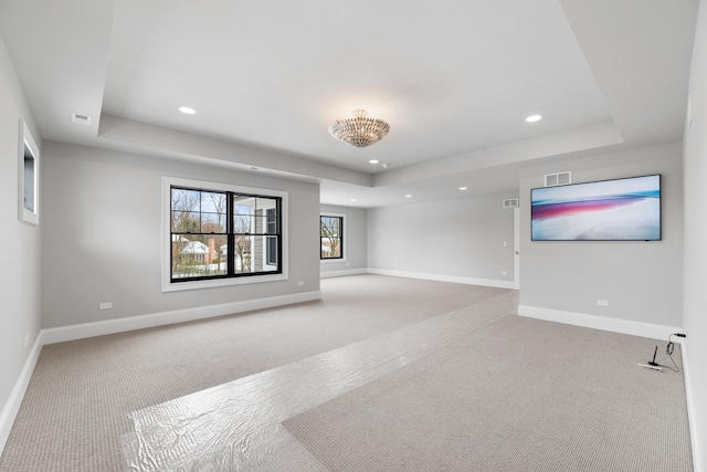 unfurnished living room with recessed lighting, a raised ceiling, carpet flooring, and baseboards