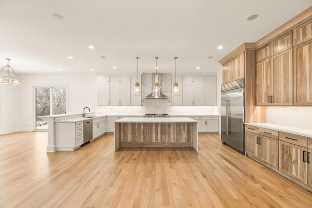 kitchen with stainless steel appliances, wall chimney range hood, a peninsula, and decorative backsplash