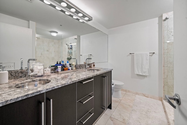 bathroom featuring double vanity, toilet, a sink, and tiled shower