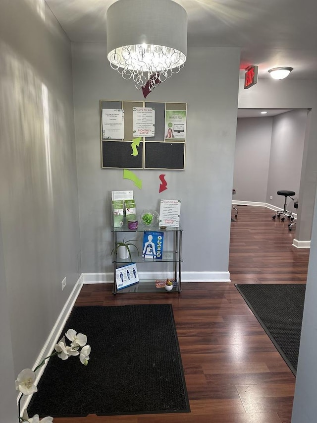 interior space with dark wood finished floors, baseboards, and an inviting chandelier