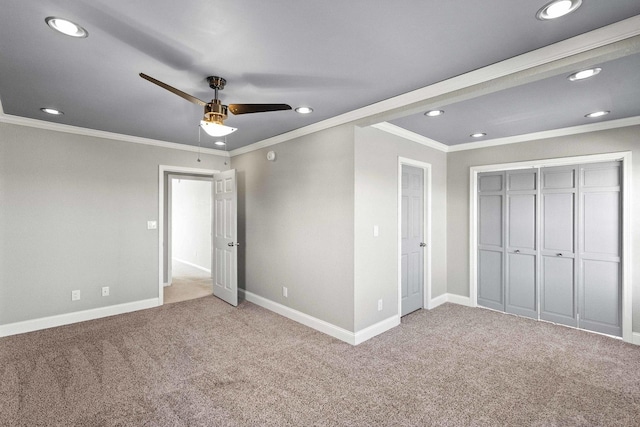 unfurnished bedroom featuring carpet, a closet, crown molding, and baseboards