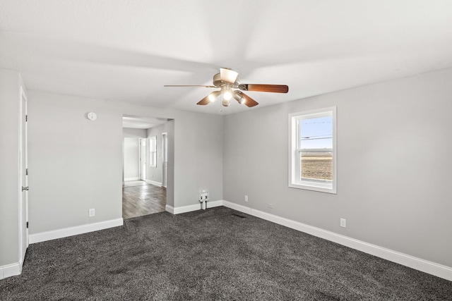 unfurnished room with dark carpet, baseboards, and ceiling fan