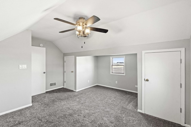 bonus room featuring lofted ceiling, a ceiling fan, visible vents, baseboards, and dark colored carpet