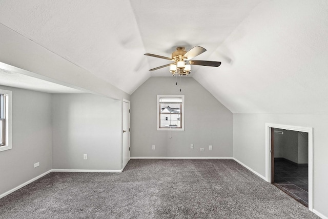 bonus room featuring lofted ceiling, a textured ceiling, ceiling fan, carpet floors, and baseboards