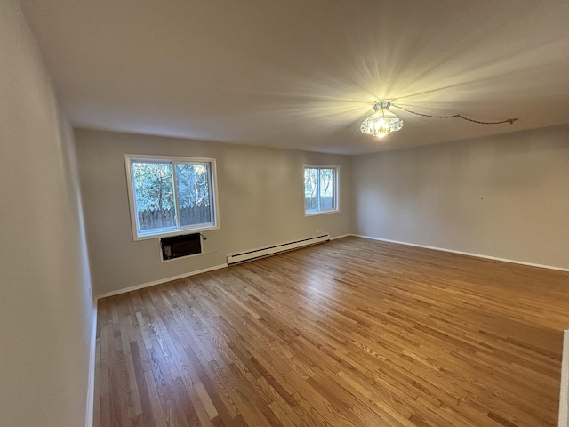 empty room featuring a baseboard radiator, baseboards, and wood finished floors