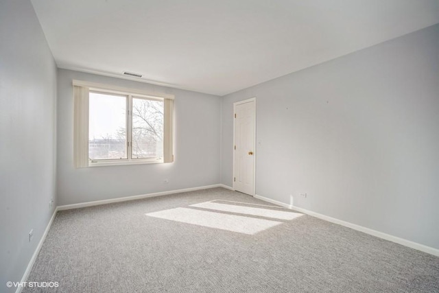 carpeted spare room with visible vents and baseboards