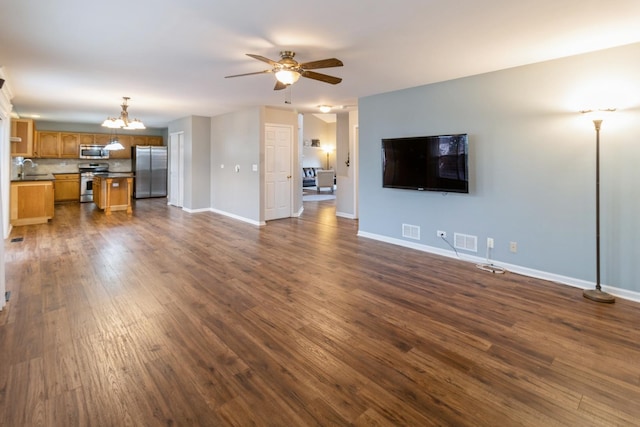 unfurnished living room with visible vents, dark wood finished floors, baseboards, and ceiling fan with notable chandelier