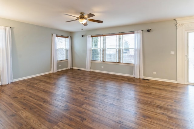 spare room featuring dark wood-style floors, ceiling fan, visible vents, and baseboards