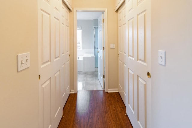 corridor featuring baseboards and dark wood-style flooring