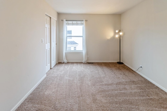 carpeted spare room with visible vents and baseboards