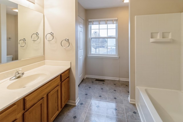 bathroom featuring a washtub, toilet, vanity, baseboards, and walk in shower